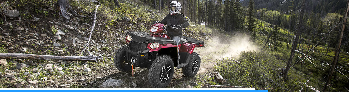 Man riding a red Honda® ATV through the woods